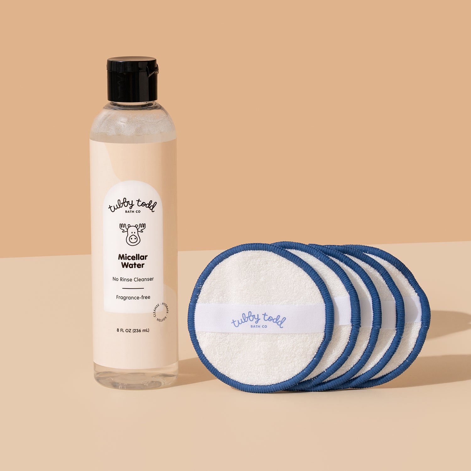 Fragrance Free Micellar Water bottle standing with the cotton pads on the beige color background.